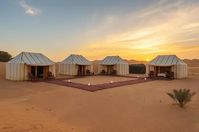 a group of tents in the desert at sunset at Ame camp in Merzouga