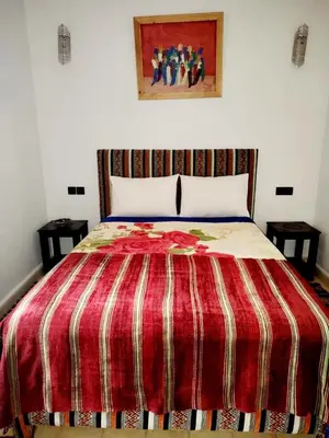 a bedroom with a bed with a red striped comforter at Ourika lodge the healing place in Tafza