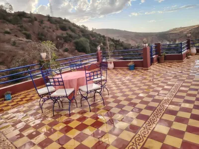 a balcony with a table and chairs on a checkered floor at Ourika lodge the healing place in Tafza