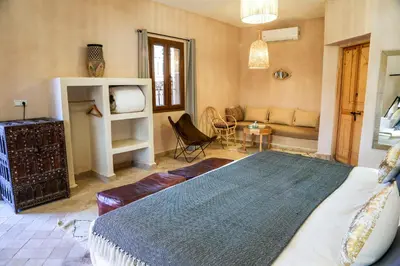 a bedroom with a bed and a living room at Riad Madu in Merzouga