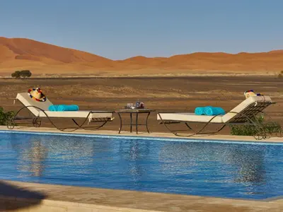 two chairs and a table next to a swimming pool at Riad Madu in Merzouga