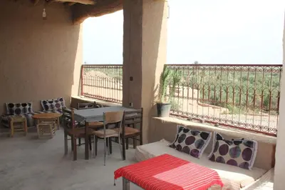 a patio with a table and chairs and a table and a balcony at Auberge Migusta in Skoura