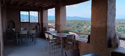 a restaurant with tables and chairs on a balcony at Auberge Migusta in Skoura