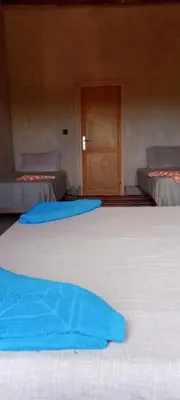 a group of three beds in a room with a door at Auberge Migusta in Skoura