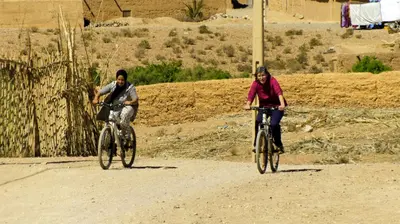 two people riding bikes on a dirt road at Auberge Migusta in Skoura