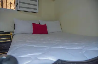 a white bed with a red pillow on it at LA casa Dar Rayan in Fès