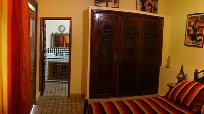 a living room with a couch and a wooden cabinet at Riad Les Chrifis Navette Aéroport 24 sur 24 in Fès