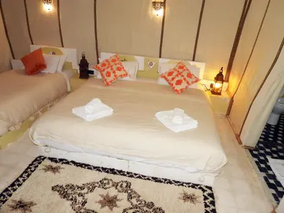 a bedroom with two beds with hats and a rug at Sleep In Luxury Tent In Desert in Merzouga