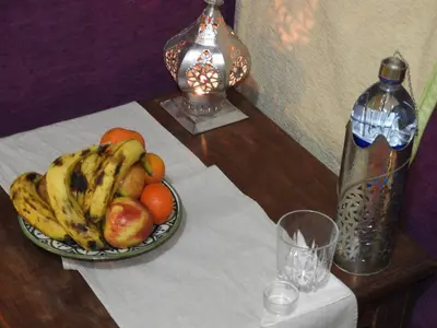 a bowl of fruit on a table next to a bottle at Sleep In Luxury Tent In Desert in Merzouga