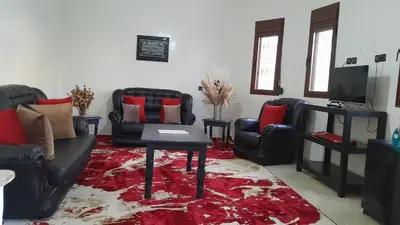 a living room with black leather chairs and a red rug at Welcome Home in Beni Mellal