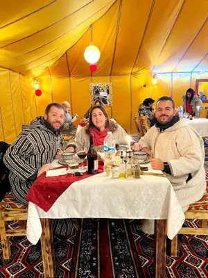a group of people sitting at a table in a tent at Morocco Luxury Camp - Merzouga Desert Retreat in Merzouga