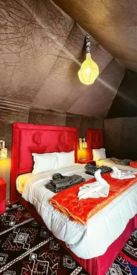 a bedroom with a red bed with clothes on it at Morocco Luxury Camp - Merzouga Desert Retreat in Merzouga