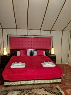 a bedroom with a red bed in a tent at Morocco Luxury Camp - Merzouga Desert Retreat in Merzouga