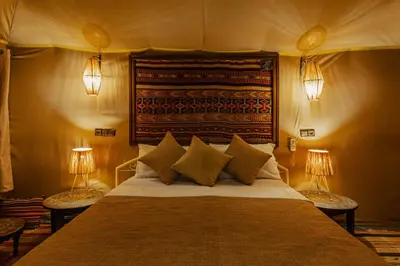 a bedroom with a large bed with two lamps at Paradis Du Sahara in Merzouga