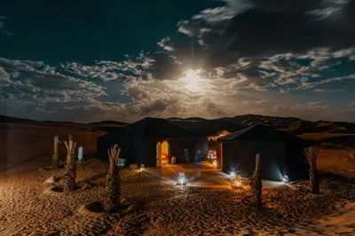 a black tent in the middle of the desert at night at Paradis Du Sahara in Merzouga
