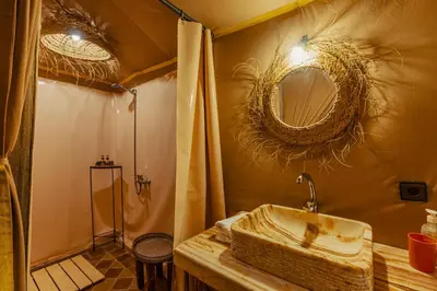a bathroom with a sink and a shower with a mirror at Paradis Du Sahara in Merzouga