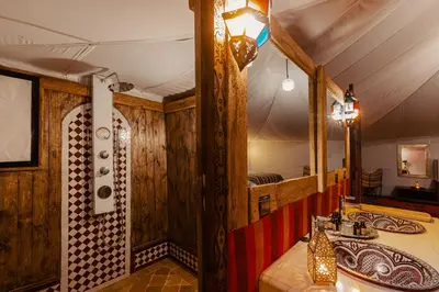 a bathroom with wooden walls and a sink and a mirror at Paradis Du Sahara in Merzouga