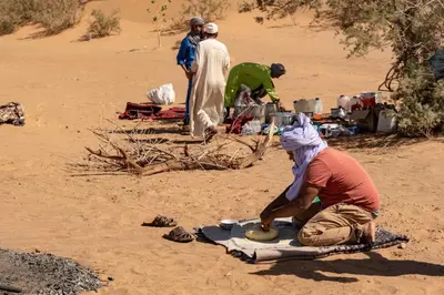 a man sitting on the sand in the desert at Tikida Camp by tinfou in Zagora