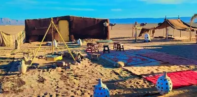 a desert encampment with a tent in the sand at Tikida Camp by tinfou in Zagora