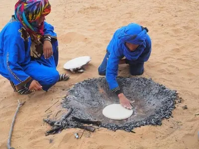 two people playing with a frisbee in the sand at Chigaga Desert Camp in Mhamid