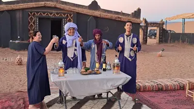 a group of three people standing around a table at Chigaga Desert Camp in Mhamid