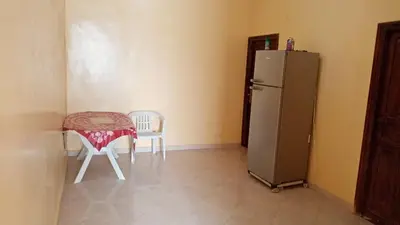 a kitchen with a refrigerator and a table and chairs at Chez zakaria guest house in Merzouga