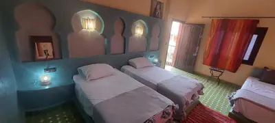 a room with three beds in a room with a mirror at Maison Vallée Du Ziz in Ouled Aissa