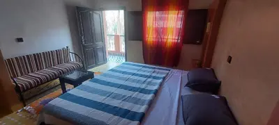 a bedroom with a bed and a couch and a window at Maison Vallée Du Ziz in Ouled Aissa