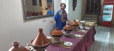 a man standing in front of a table with vases at Maison Vallée Du Ziz in Ouled Aissa