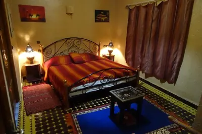 a bedroom with a bed with a red bedspread at Maison Vallée Du Ziz in Ouled Aissa