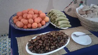 a table with bowls of fruit and bowls of nuts at Maison Vallée Du Ziz in Ouled Aissa