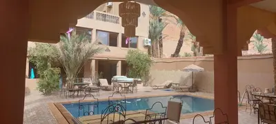 a courtyard with a pool and tables and chairs at Maison Vallée Du Ziz in Ouled Aissa