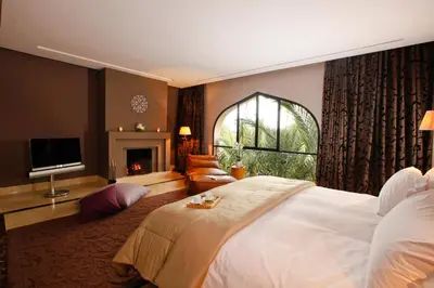 a bedroom with a large white bed and a fireplace at Palais Namaskar in Marrakech