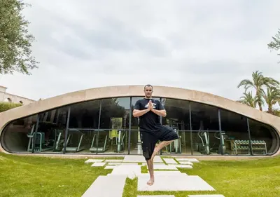 a man doing a yoga pose in front of a building at Palais Namaskar in Marrakech