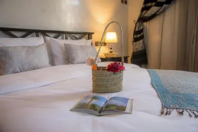a basket of flowers and a book on a bed at Ksar Elkabbaba Kasbah & SPA in Skoura
