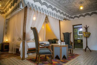a bedroom with a bed and a table and chairs at Ksar Elkabbaba Kasbah & SPA in Skoura