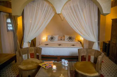 a bedroom with a bed and two chairs and a table at Ksar Elkabbaba Kasbah & SPA in Skoura