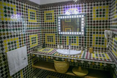 a tiled bathroom with a sink and a mirror at Ksar Elkabbaba Kasbah & SPA in Skoura