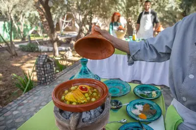 a person pouring a pot of food onto a table at Ksar Elkabbaba Kasbah & SPA in Skoura