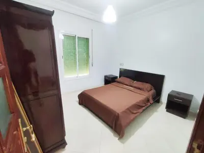 a bedroom with a bed and a wooden cabinet at SkyRise 1 Khemisset 2 bedrooms in Khemisset