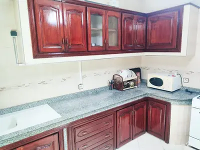 a kitchen with wooden cabinets and a microwave at SkyRise 1 Khemisset 2 bedrooms in Khemisset