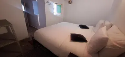 a bedroom with a bed with white sheets and black pillows at Riad Fes EL KAID in Fès