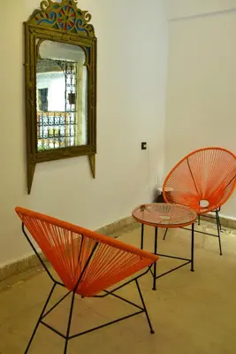 two orange chairs and a table and a mirror at Riad Fes EL KAID in Fès
