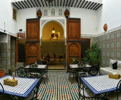 a living room with tables and chairs in a room at Riad Fes EL KAID in Fès