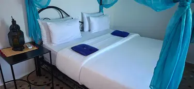 a bedroom with two white beds with blue curtains at Riad Fes EL KAID in Fès
