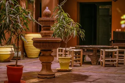 a pillar in a courtyard with potted plants and a table at Riad Kasbah Omar in Ourika
