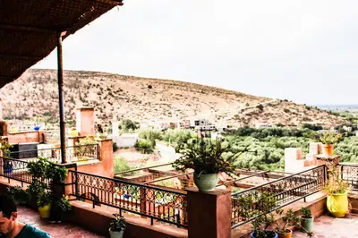 a man sitting on a balcony looking at a mountain at Riad Kasbah Omar in Ourika