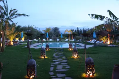a pathway leading to a pool with lights in the grass at VILLA CATHERINE MARRAKECH in Marrakech