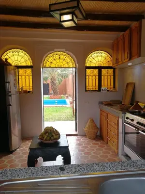 a kitchen with stained glass windows and a table with a bowl of fruit at Chez Kossai Atlas Farm in Chtawna