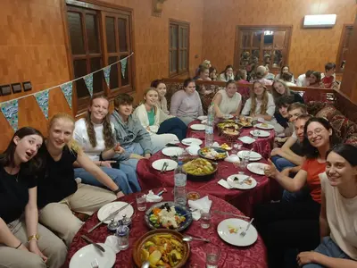 a group of people sitting around a table with food at Kasbah La Famille Berbère in Boumalne